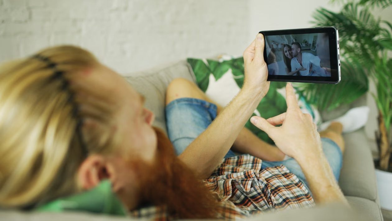 An image of a man watching a video on a tablet